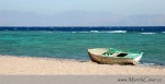 Osamělá loďka na pobřeží Rudého moře v Aqabském zálivu. V pozadí hory Saudské Arábie